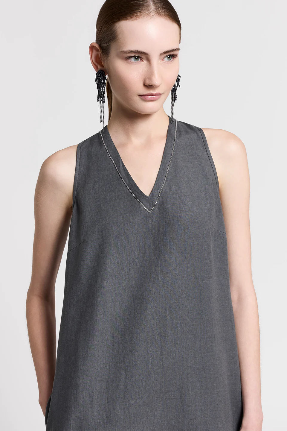 Woman wearing a blue gray sleeveless top on a light gray background.