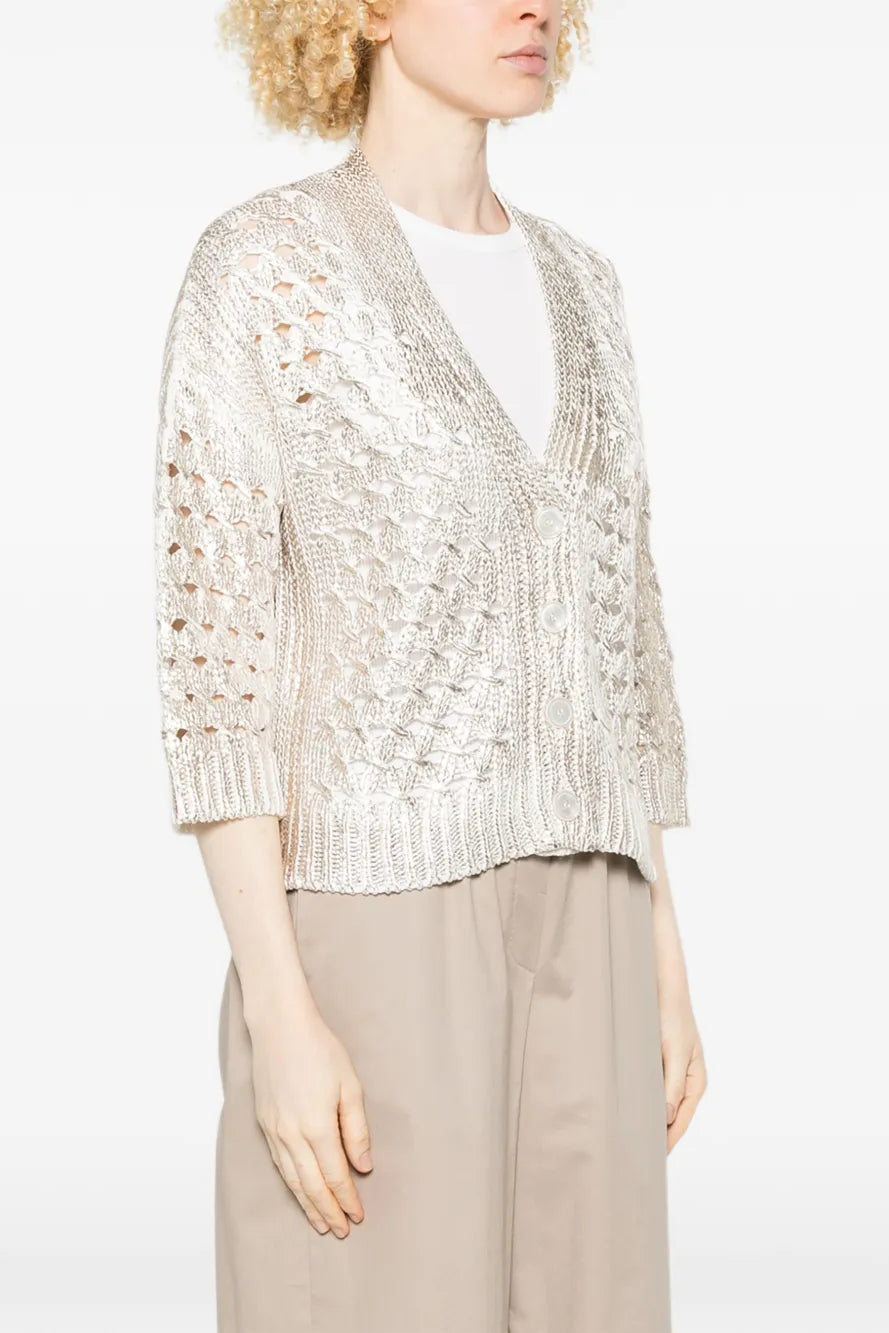 Woman wearing a gold sequin cardigan over a white top and beige pants on a white background.