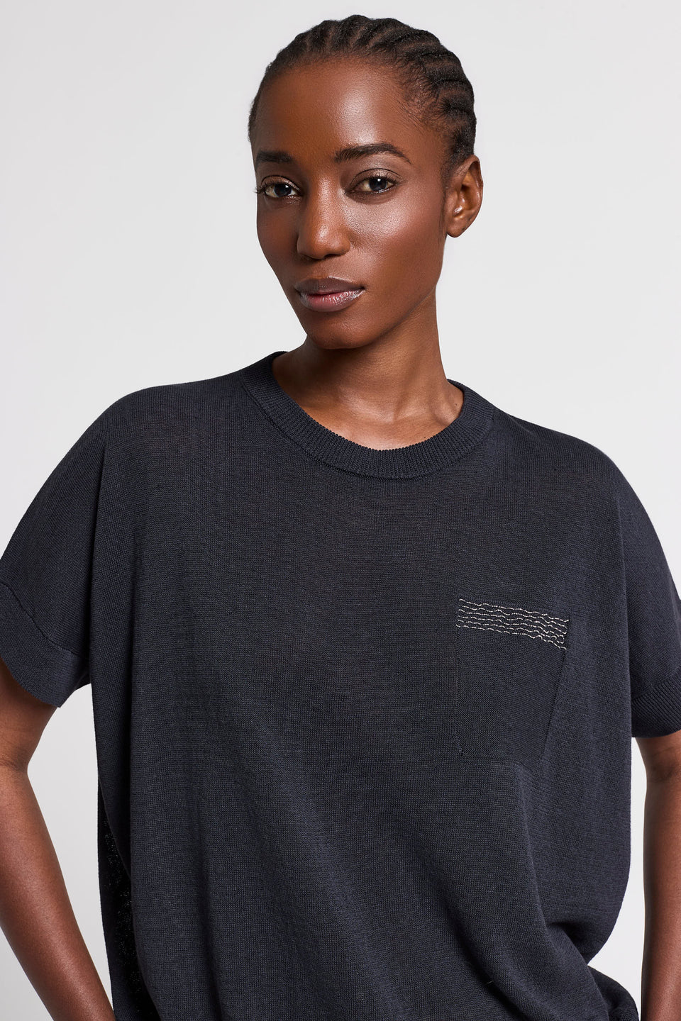 Woman wearing a navy t-shirt with a pocket on a white background.