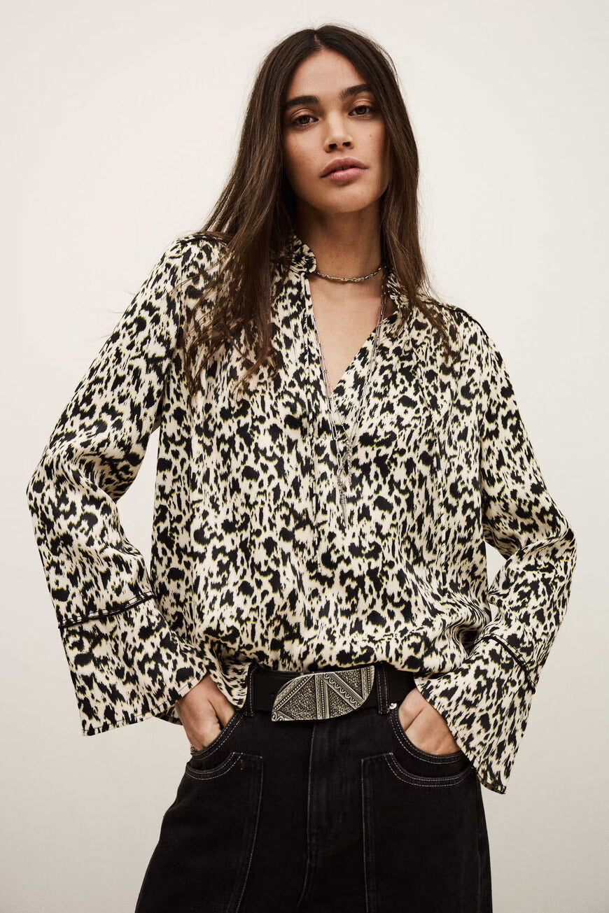 Woman wearing a leopard print blouse with a neutral background.