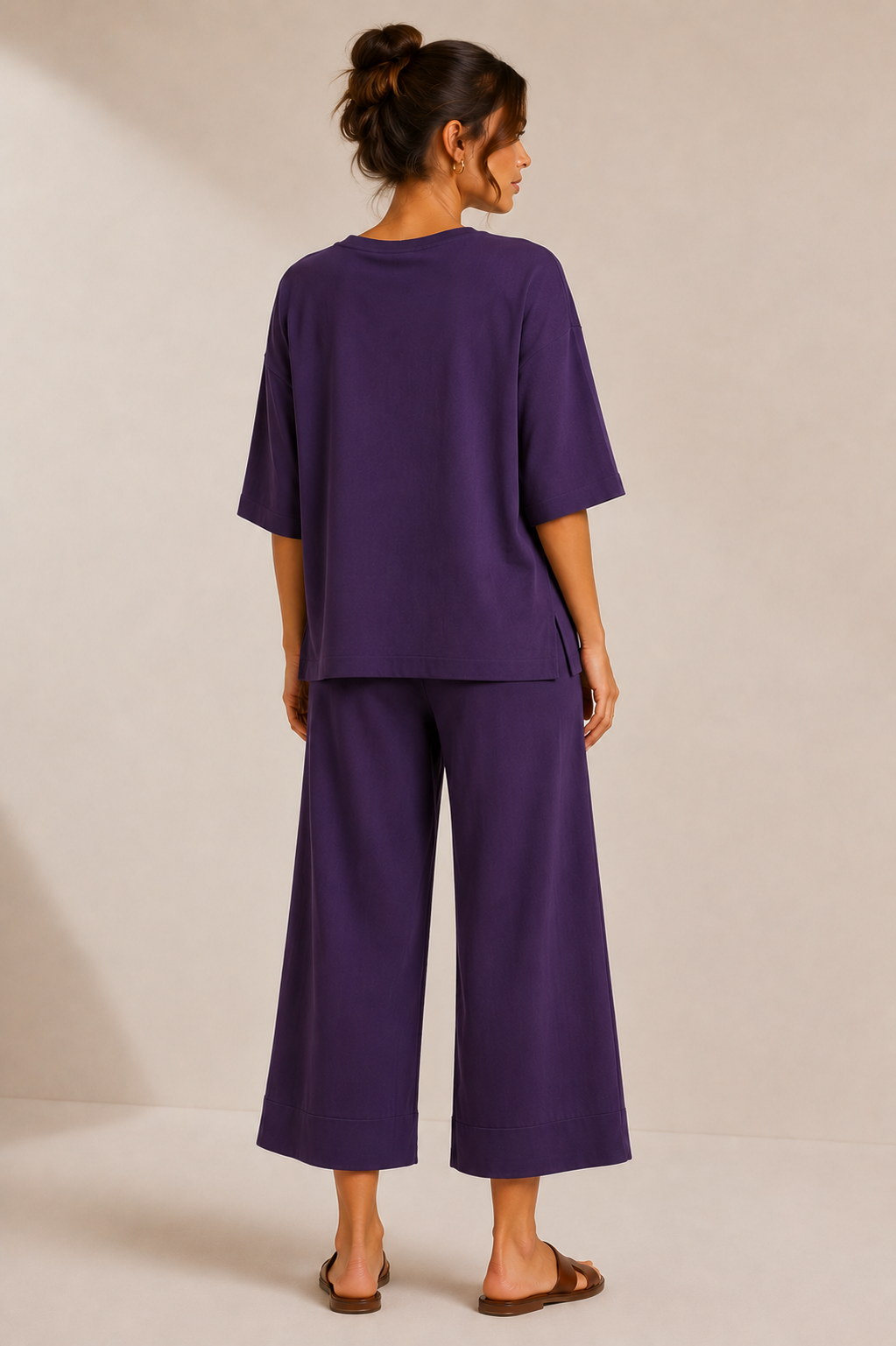 Back view of the QL2 Costanza two-piece set in deep plum, showing the relaxed top, side slits, and wide-leg cropped pants.