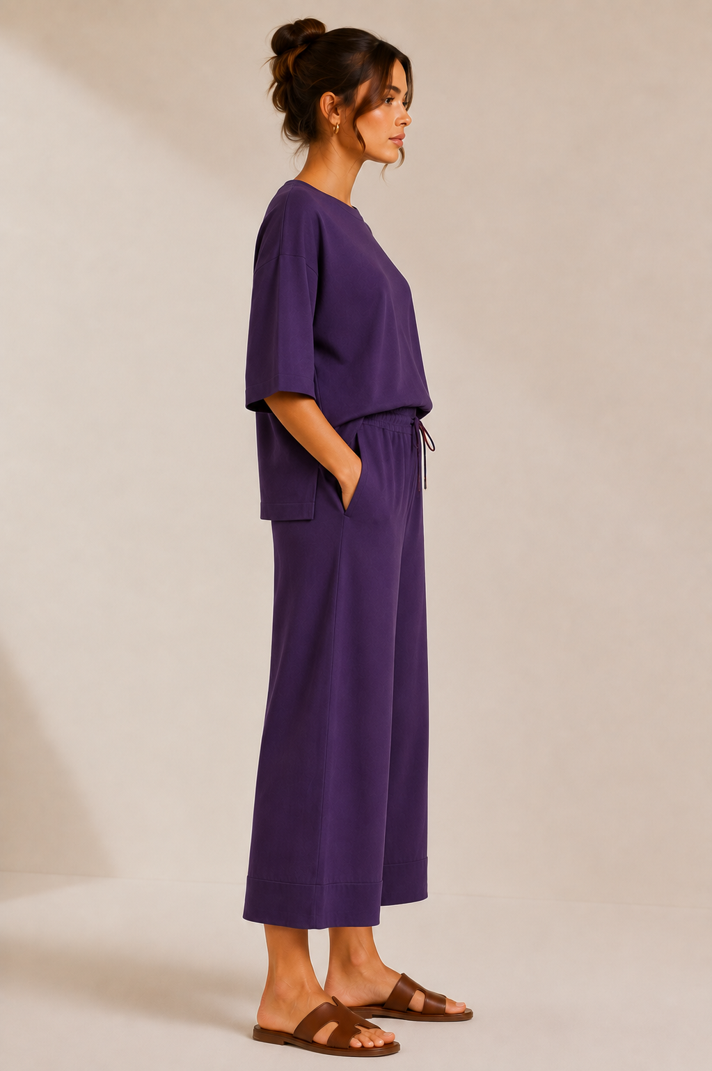 Side view of the QL2 Costanza two-piece set in deep plum, showing the relaxed silhouette, elbow-length sleeves, side slit, and wide-leg cropped pants.