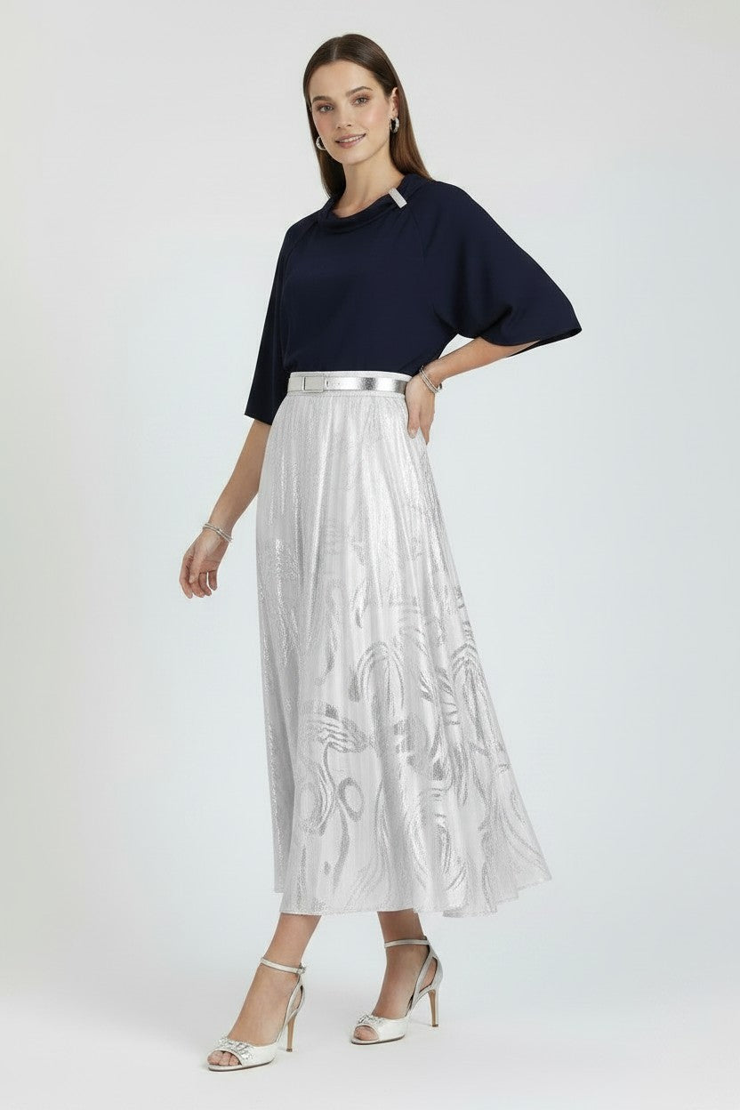 Woman wearing a navy top and white embroidered skirt on a white background.