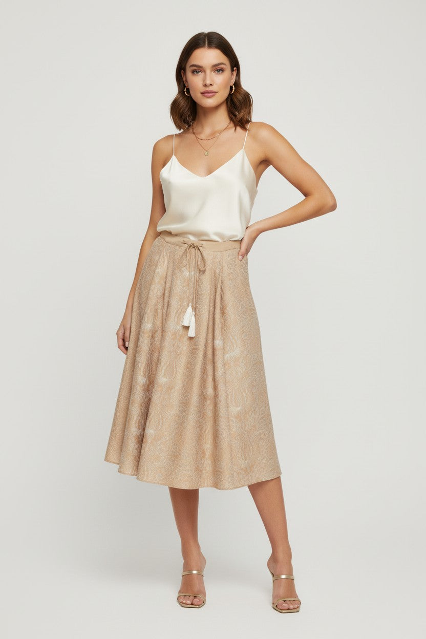 Woman wearing a white top and beige skirt on a plain background.