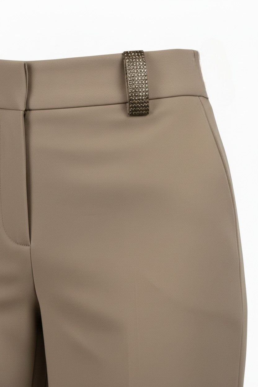 Beige pants with a jeweled belt buckle on a white background.