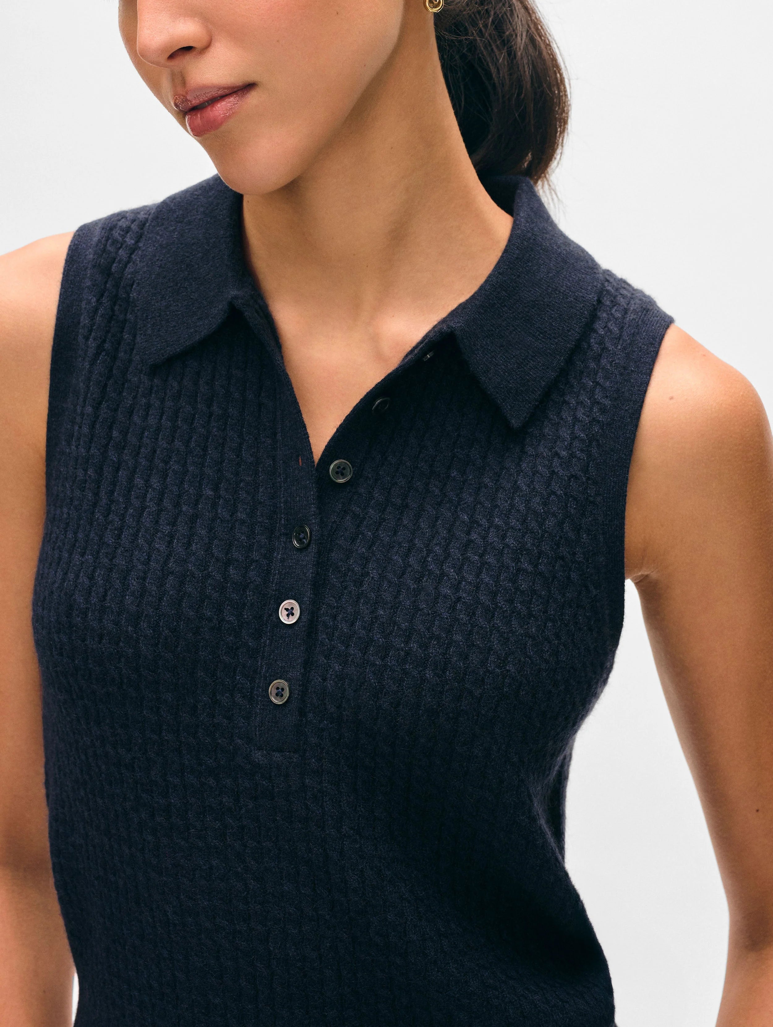 Navy sleeveless knitted top worn by a woman on a light gray background.
