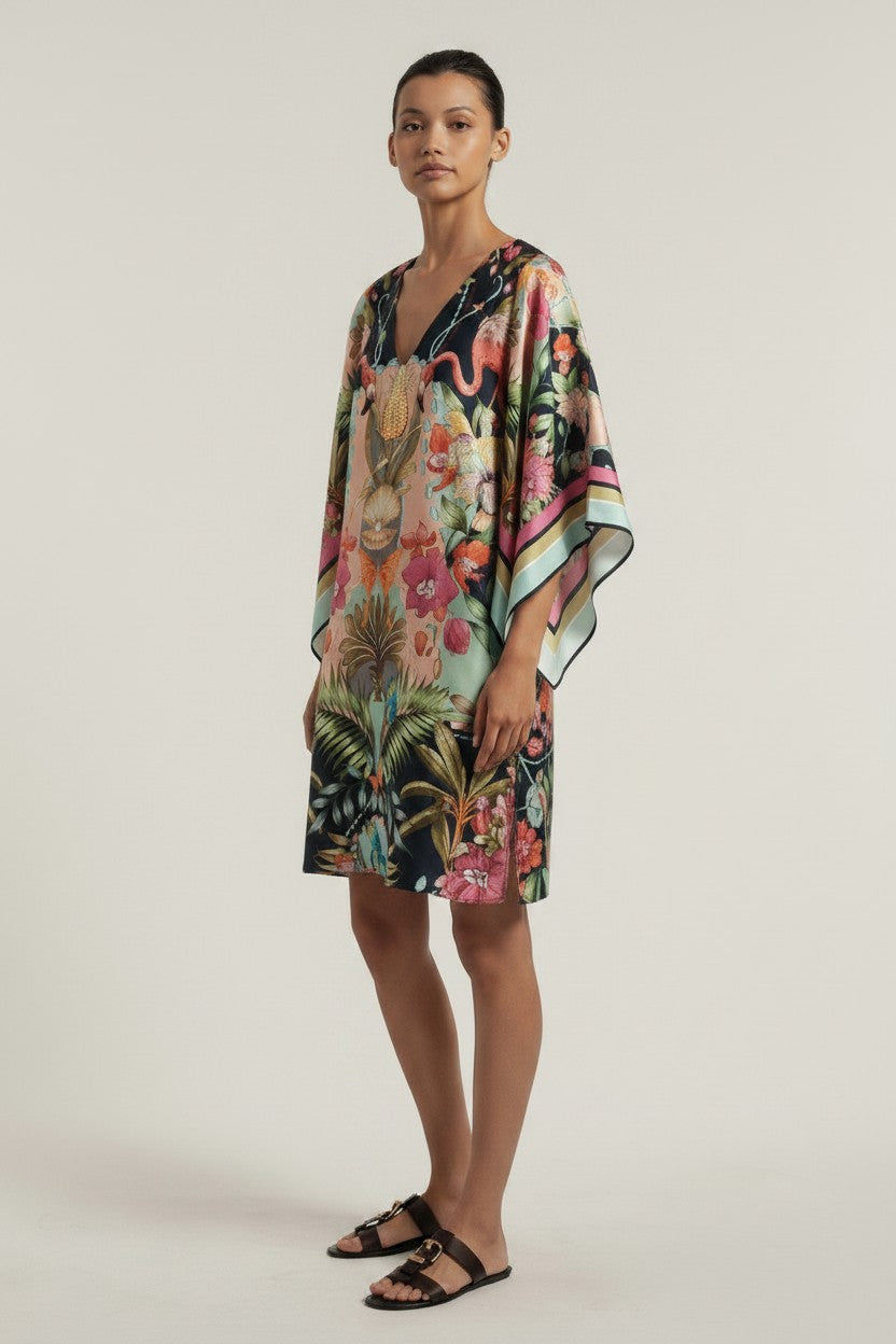 Woman wearing a colorful floral dress on a plain background.