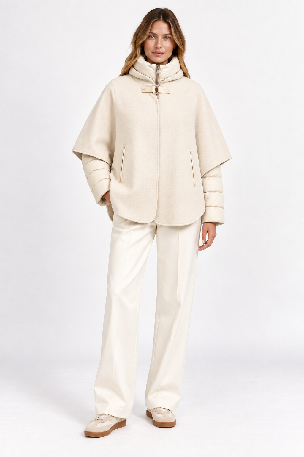 Model wearing cream cashmere cape layered over a quilted puffer jacket, front view.