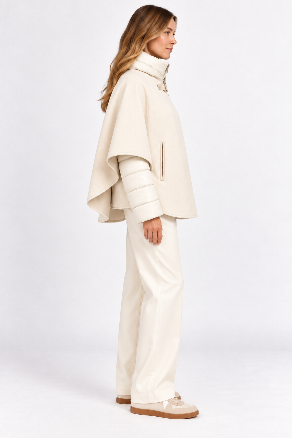 Model wearing cream cashmere cape with quilted puffer jacket, side view.