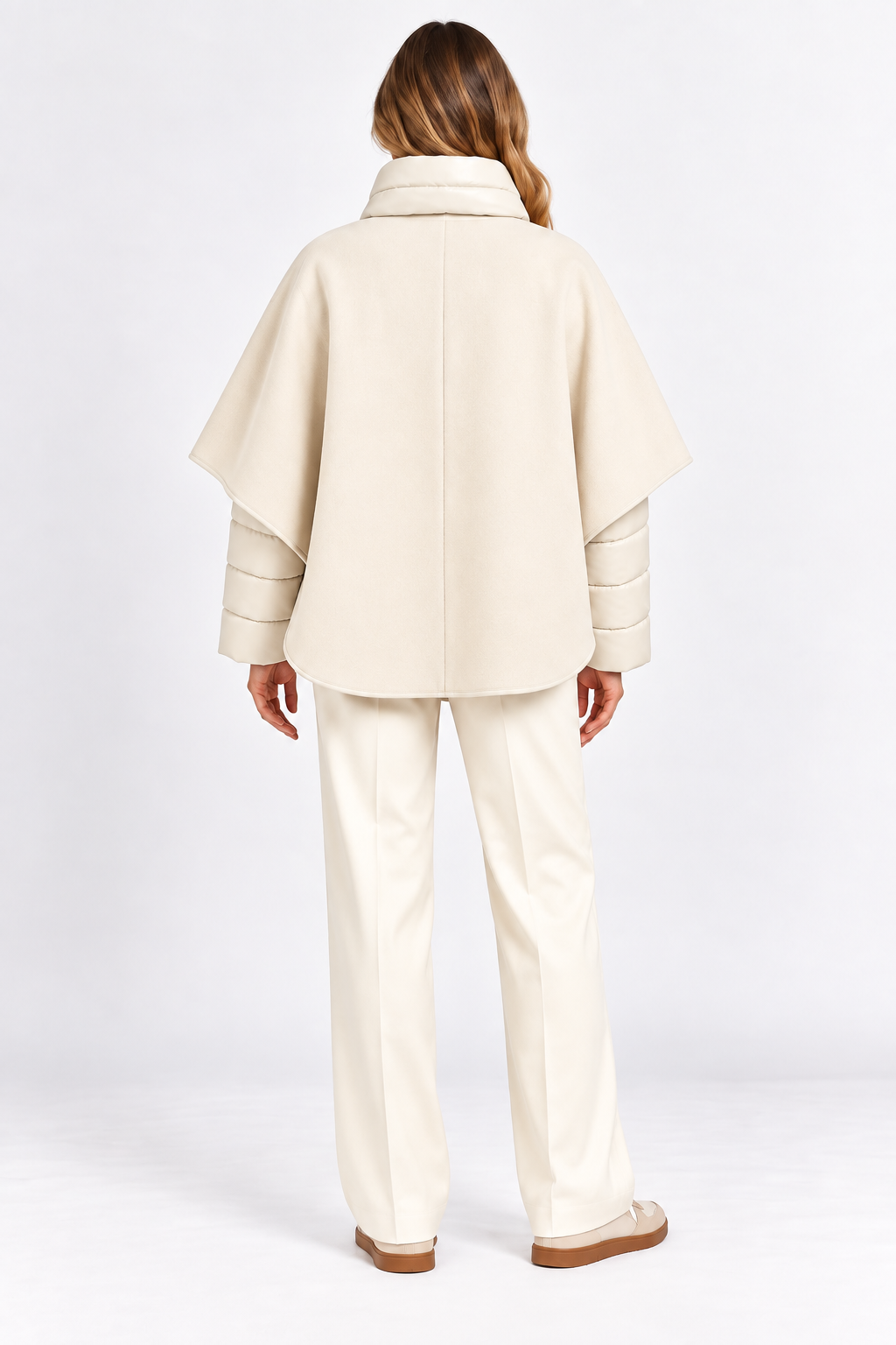 Model wearing cream cashmere cape with quilted puffer jacket, back view.
