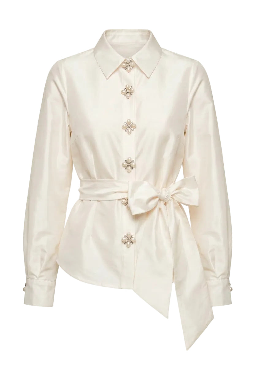 White blouse with floral embellishments and a tie waist on a white background.