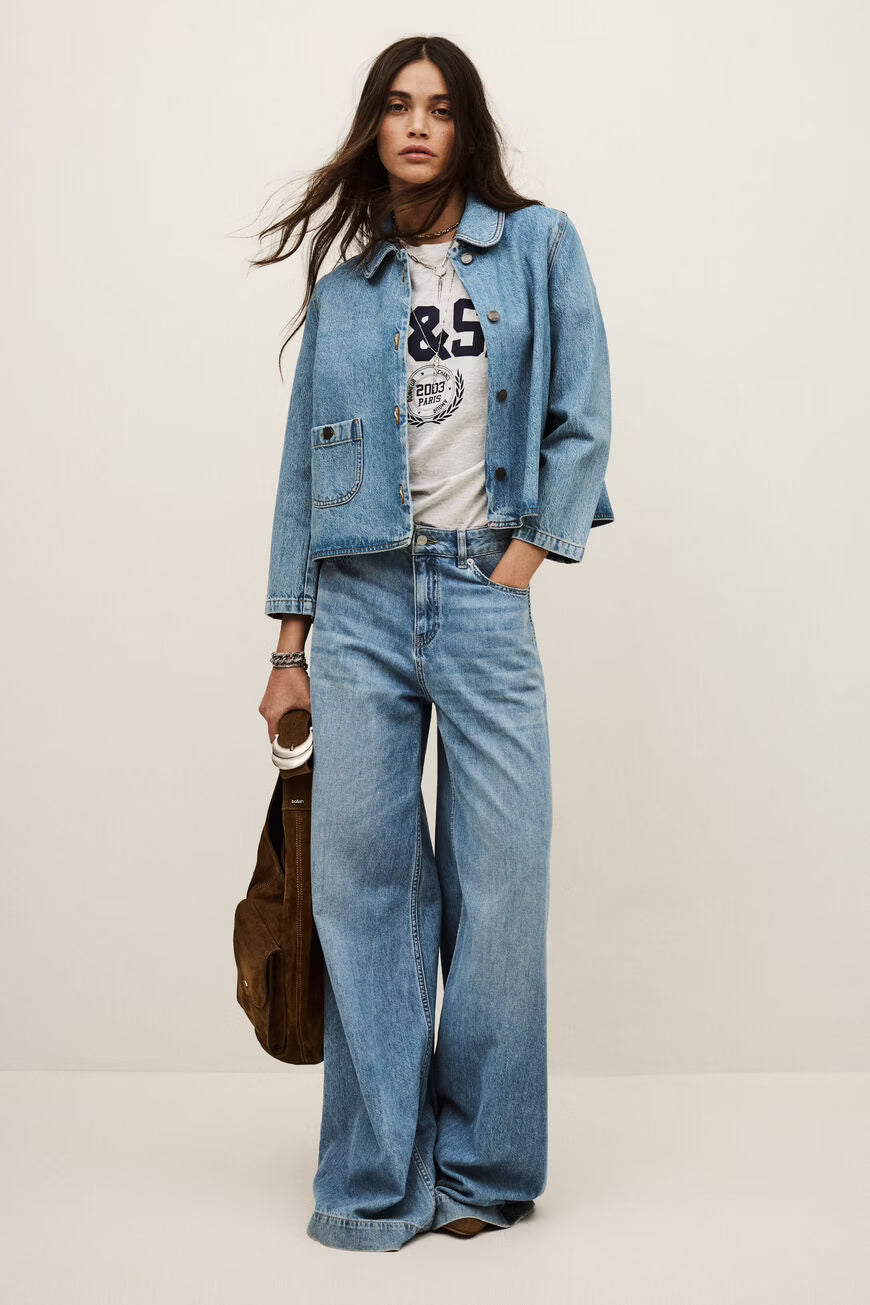 Woman wearing a denim jacket and jeans with a white background.