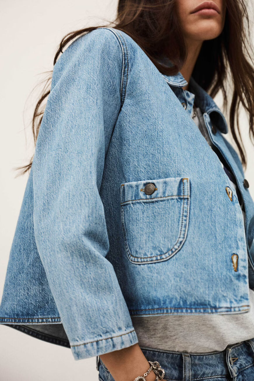 Close-up of a woman wearing a blue denim jacket with a neutral background.