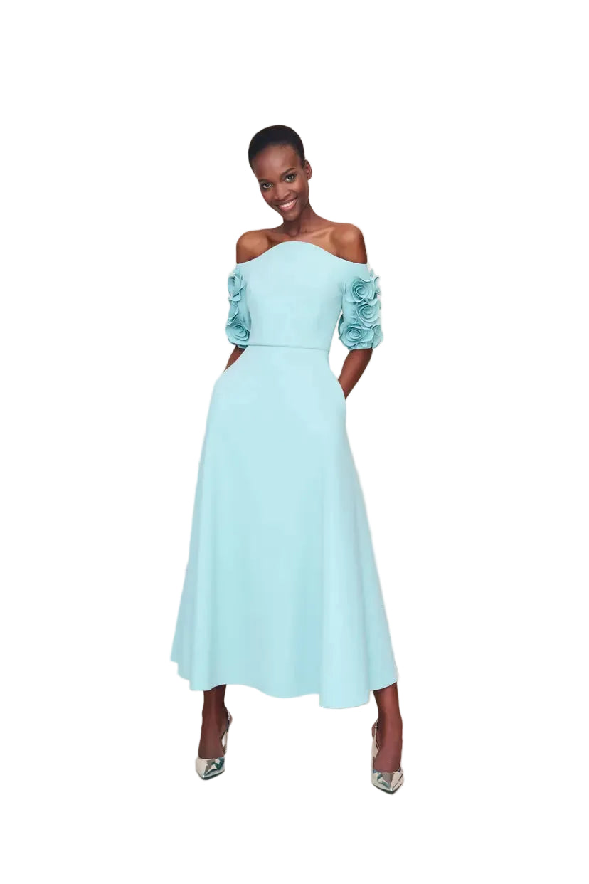 Woman wearing a light blue off-shoulder dress with floral sleeves against a white background.