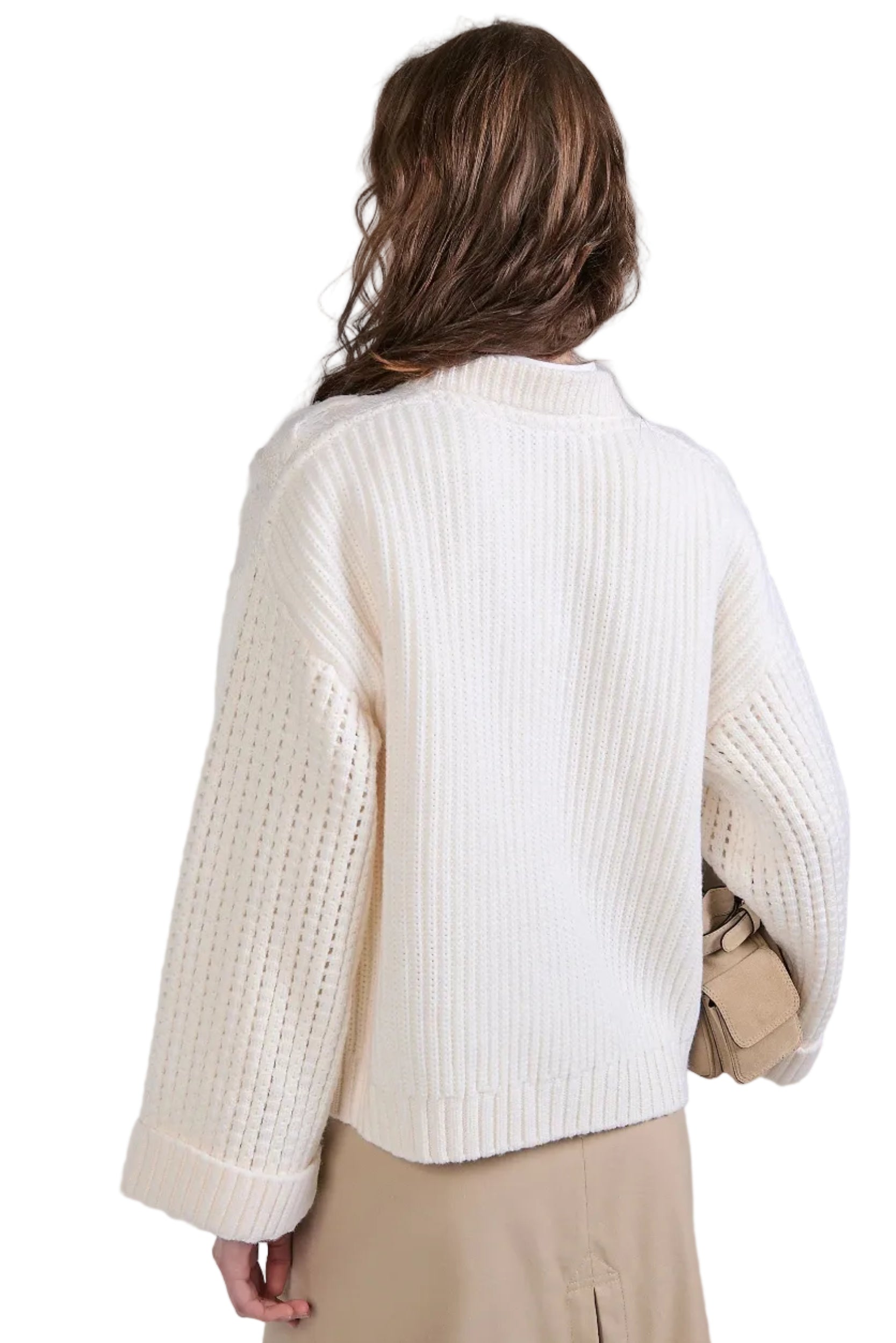 Person wearing a white cable knit sweater against a plain background.