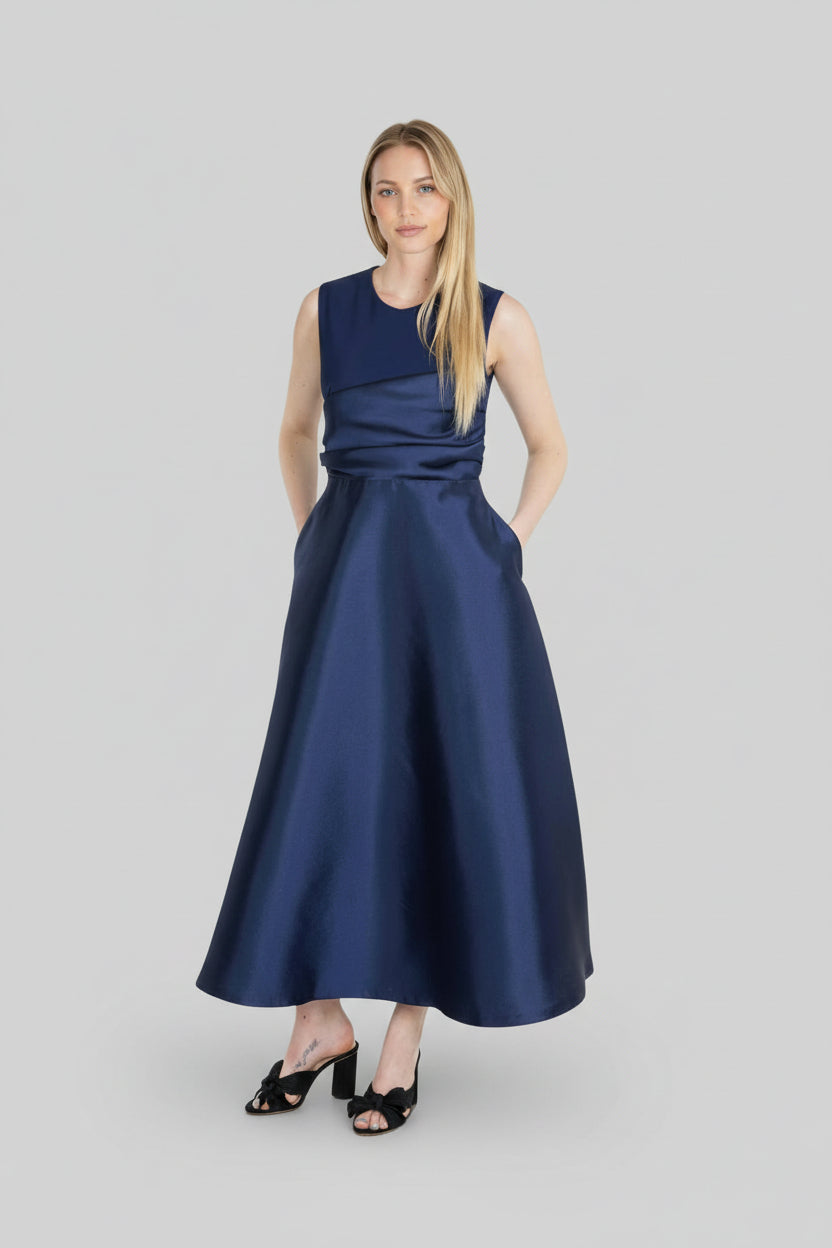 Woman wearing a navy blue dress on a light gray background.