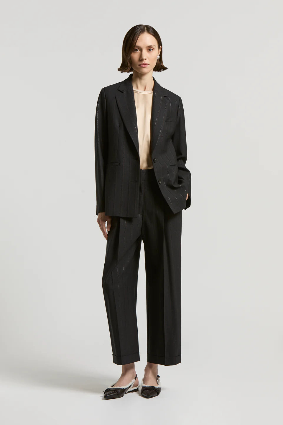 Woman wearing a black suit with a white background.