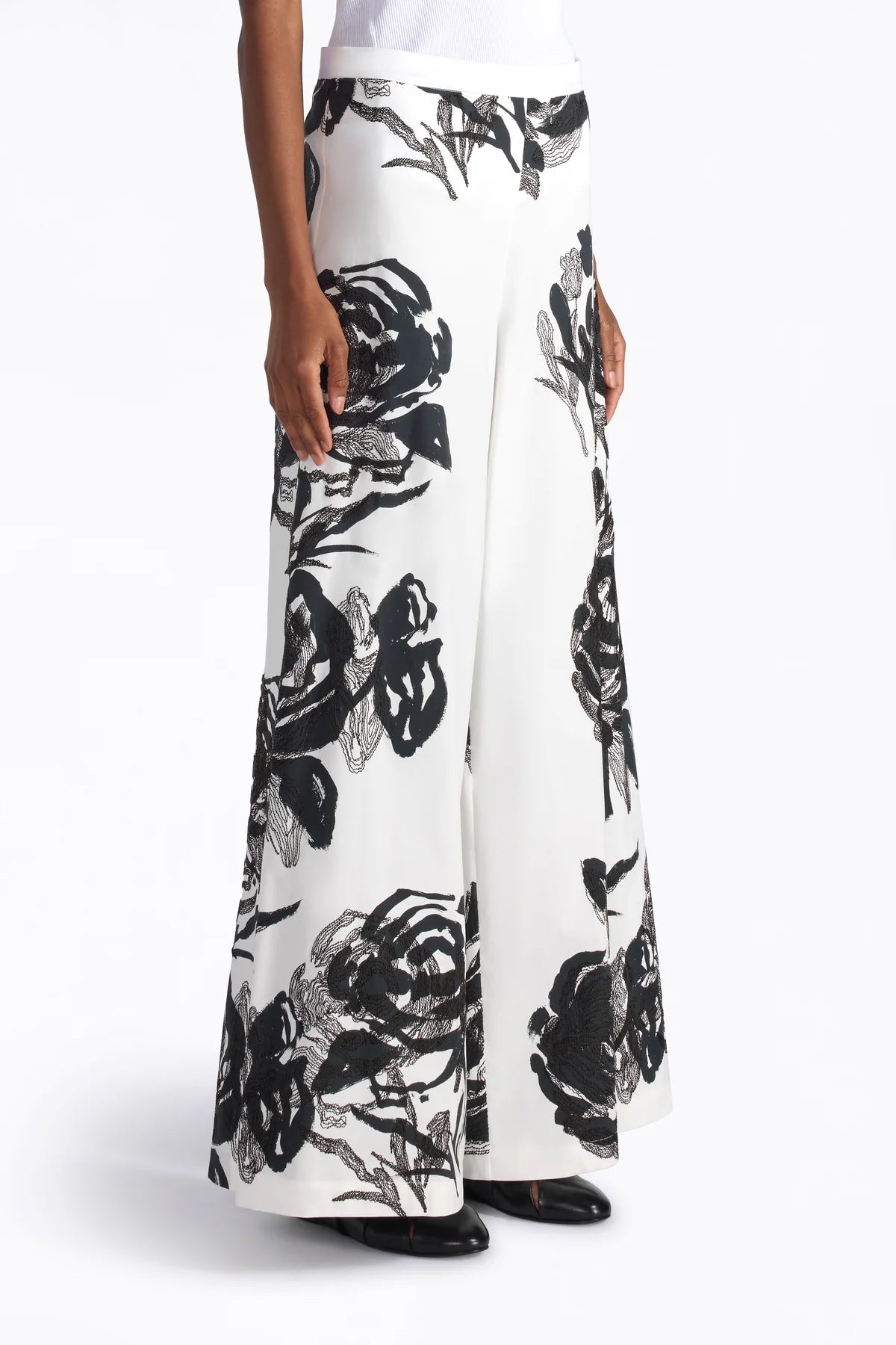 White pants with black floral pattern worn by a person on a white background.