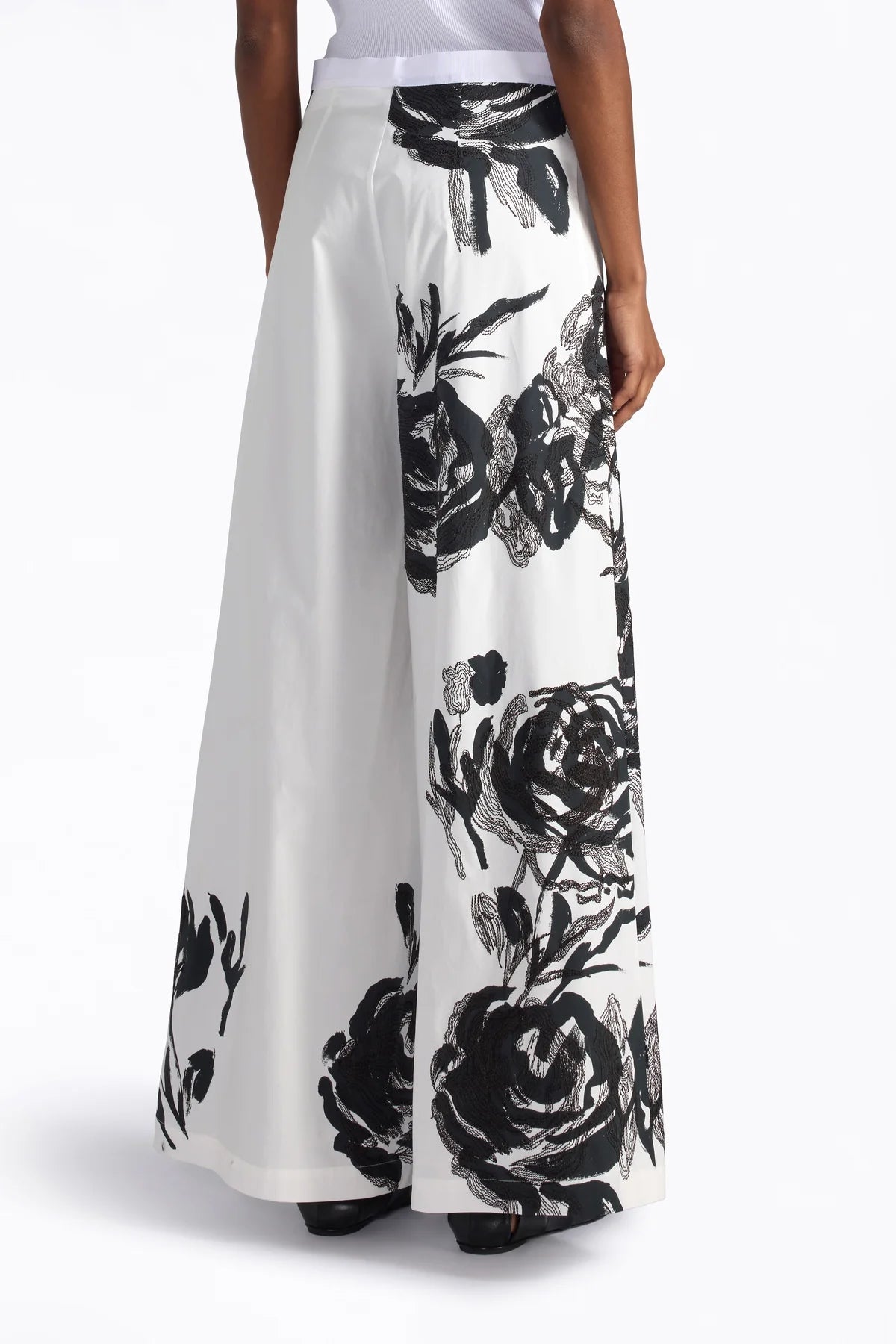 White pants with black floral pattern worn by a person on a white background.