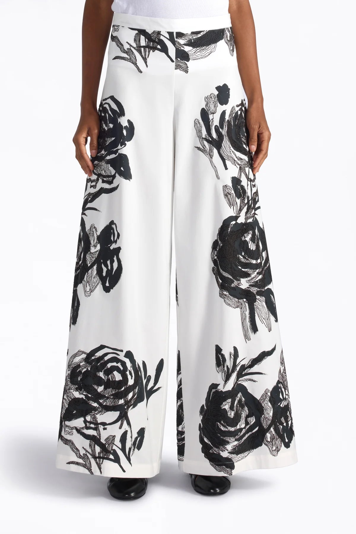 White pants with black floral pattern worn by a person on a white background.