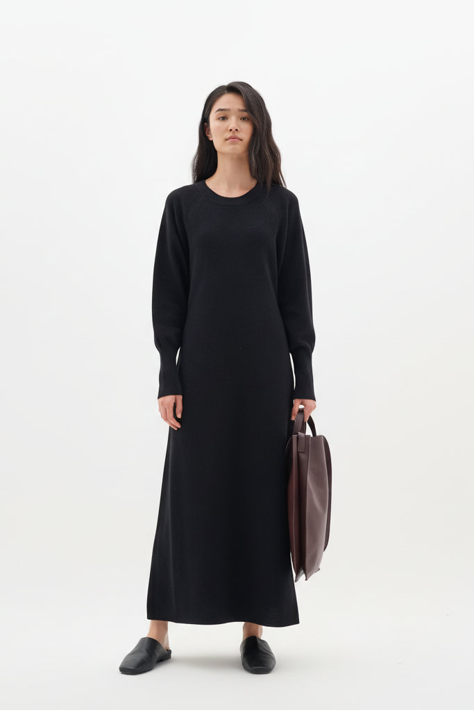 Woman wearing a black dress holding a brown bag on a white background