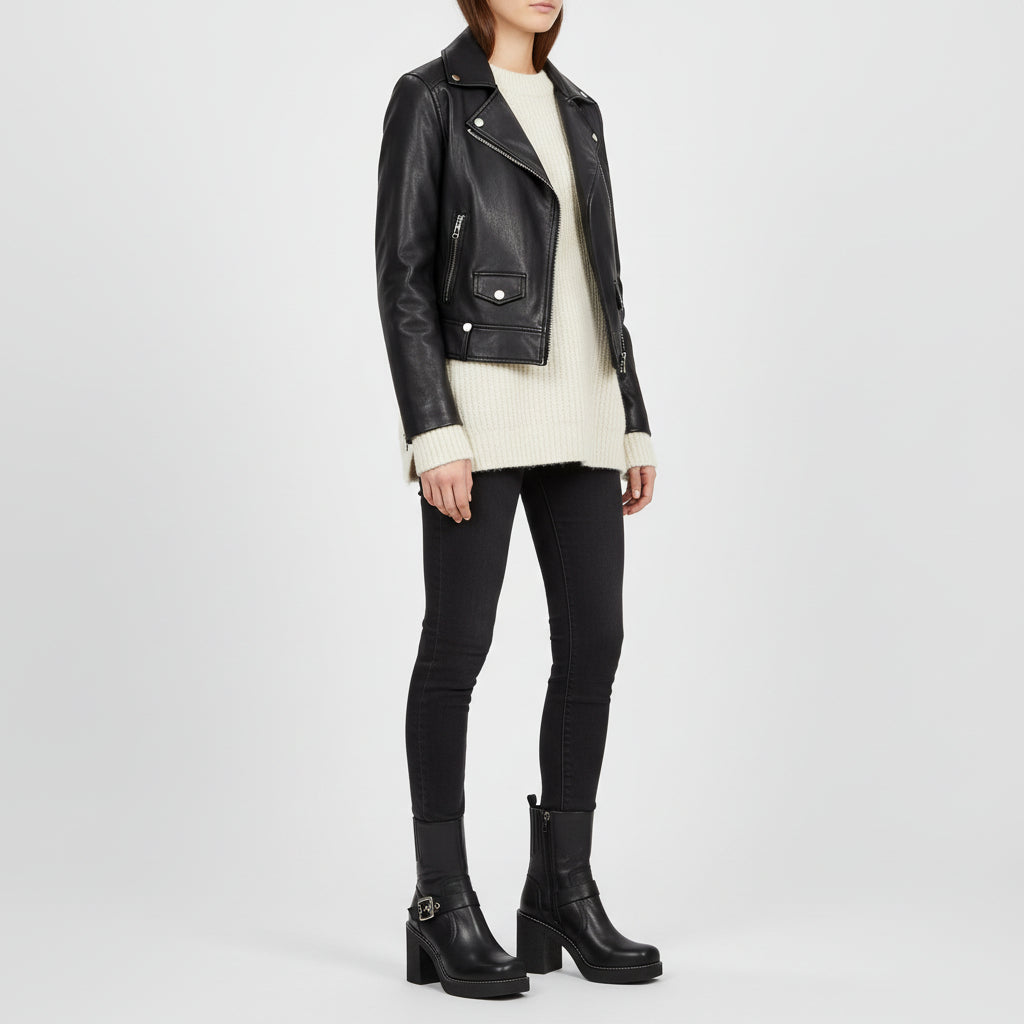 Person wearing a black leather jacket, white sweater, black pants, and black boots on a white background