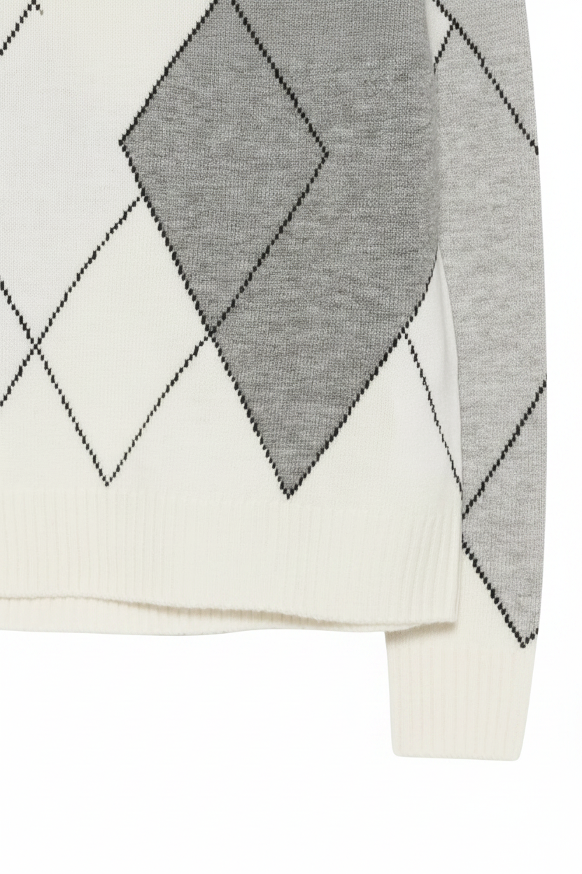 Close-up of a knit sweater showing an argyle pattern with alternating white and gray diamonds outlined in black, plus ribbed hem and sleeve edges.