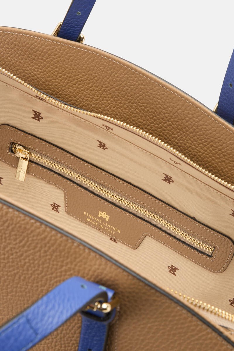 Close-up of the inside of a brown handbag with blue straps and gold zipper.