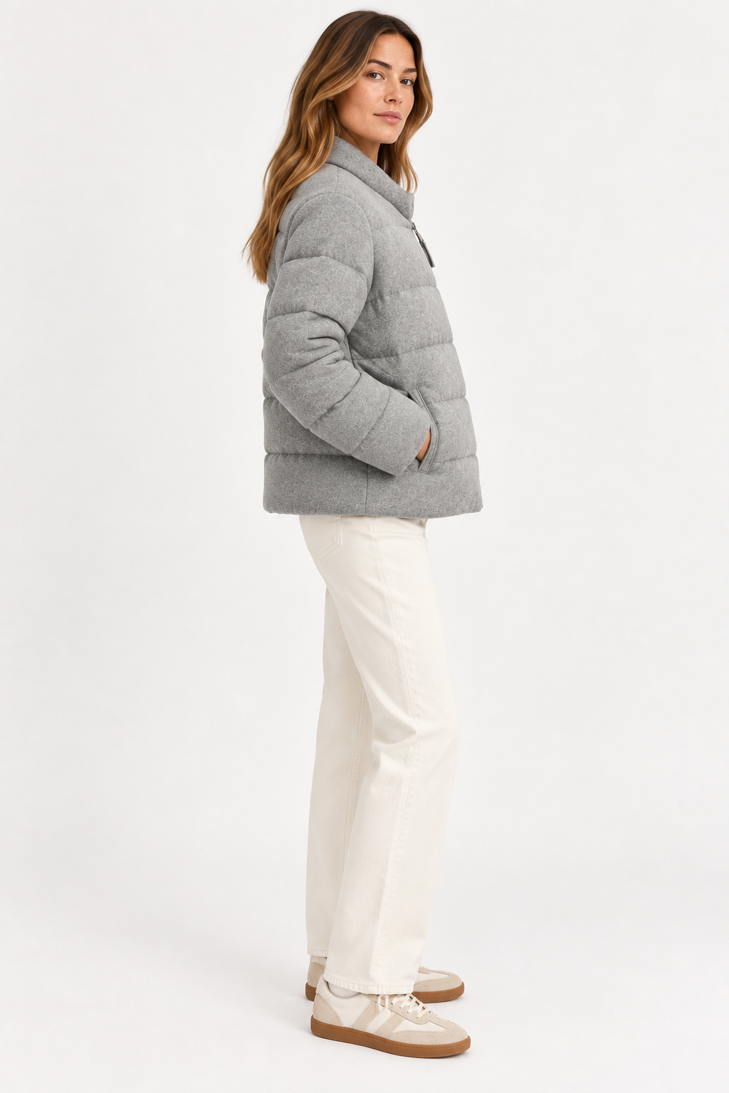 Model wearing the gray Allude cashmere quilted jacket with cream pants, shown from the side.