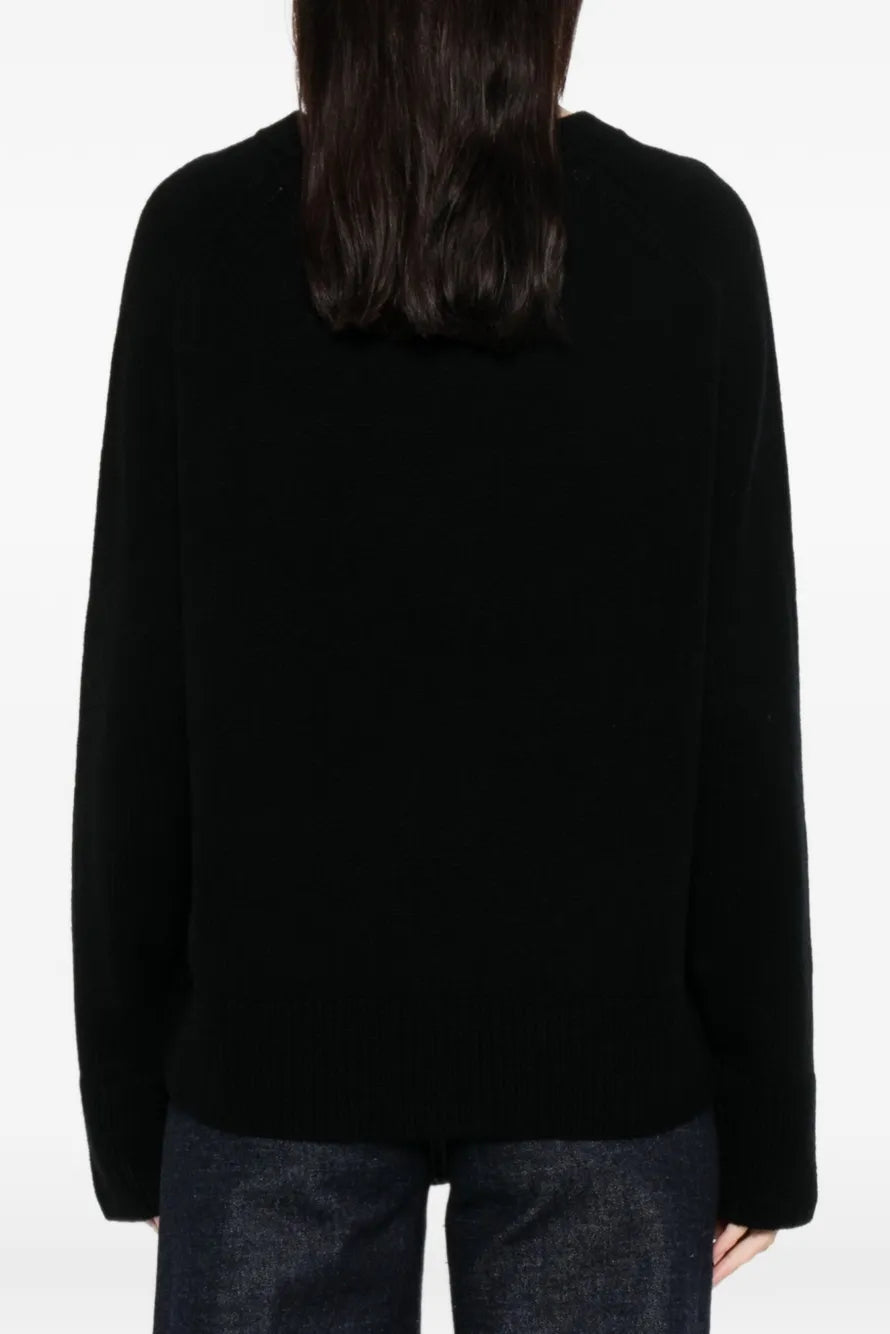 Woman wearing a black sweater on a white background.
