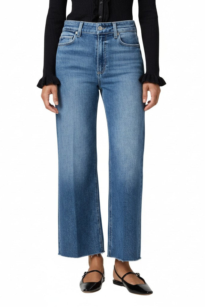 Woman wearing blue jeans and a black top on a white background.