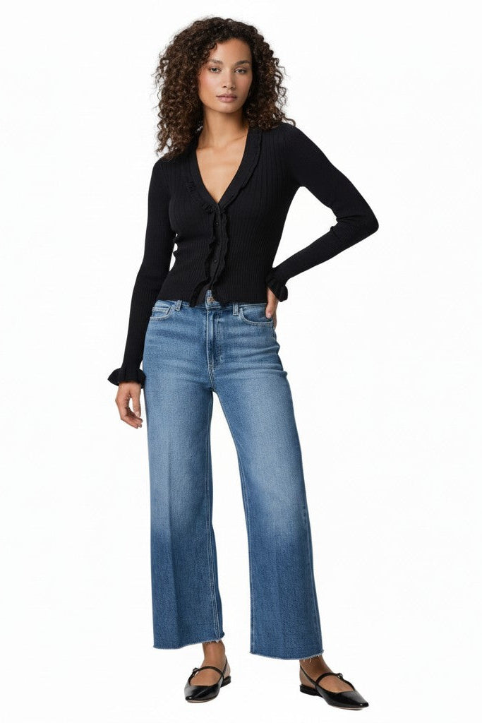 Woman wearing a black top and blue jeans on a white background.