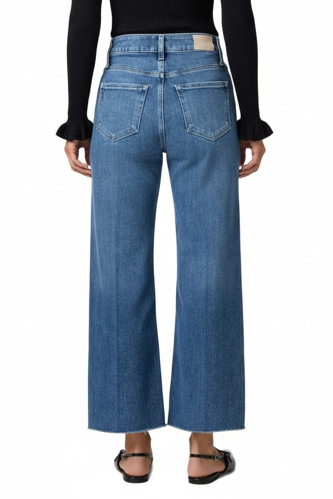 Back of a woman wearing wide leg jeans on a white background.