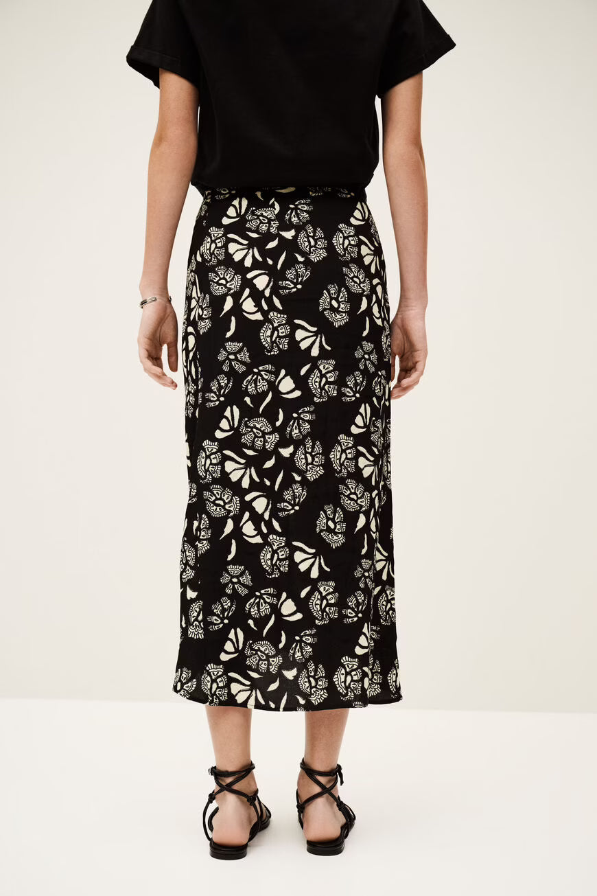 Person wearing a black floral patterned skirt on a white background