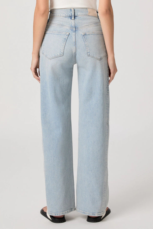 The back of a woman wearing light blue jeans on a white background.