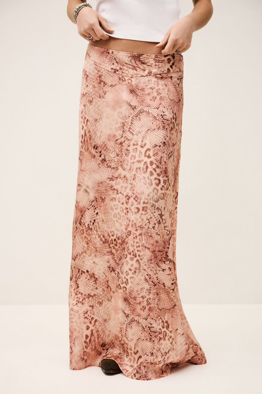 Woman wearing a long, patterned skirt on a plain background.