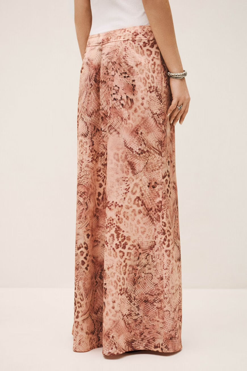 Woman wearing a patterned skirt on a plain background.