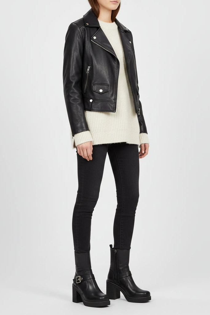 Person wearing a black leather jacket, white sweater, black pants, and black boots on a white background.