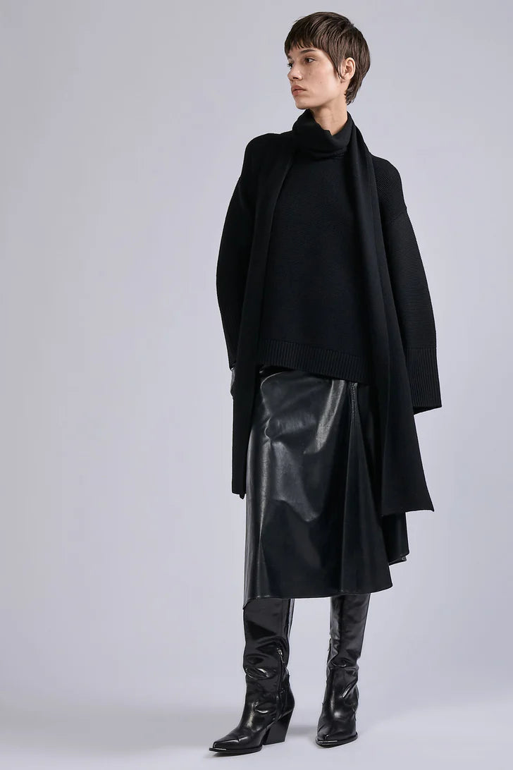 Person wearing a black coat, leather skirt, and boots on a light gray background.