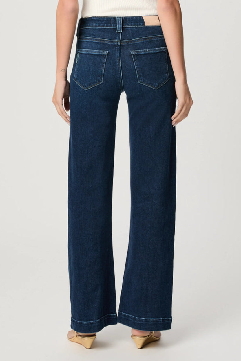Person wearing dark blue wide-leg jeans on a white background.
