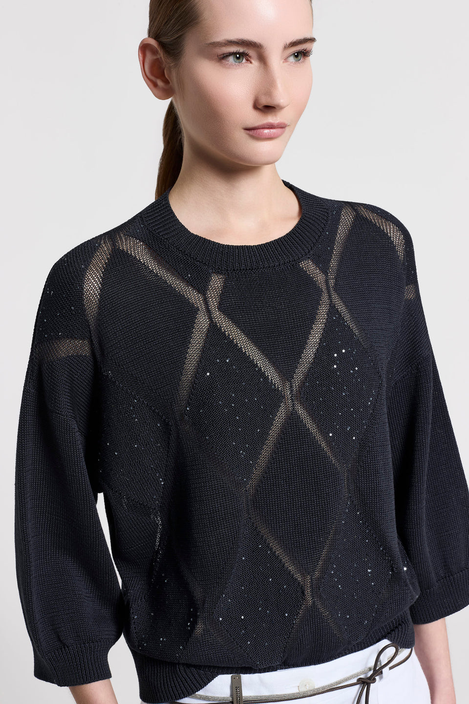 Close-up of a woman wearing a dark blue sweater with geometric pattern on a white background.