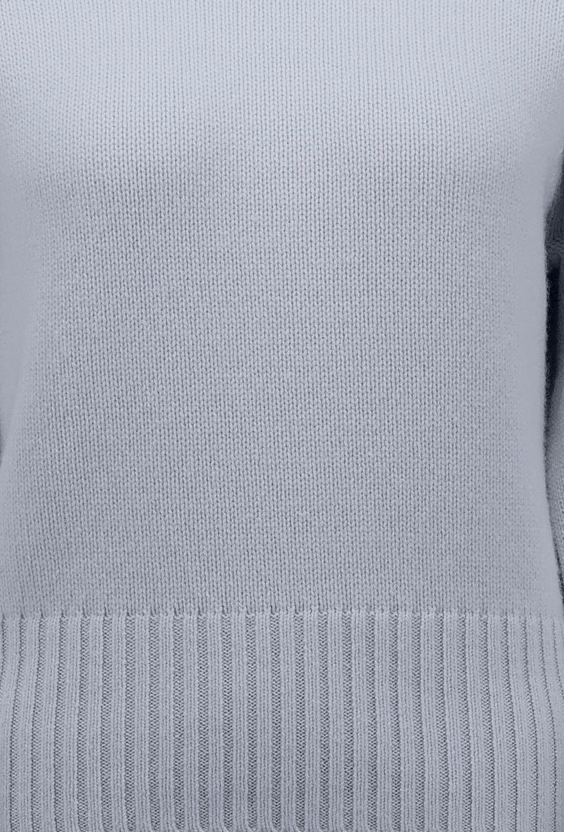 Close-up of a light blue knit sweater showing the ribbed hem and fine knit texture.