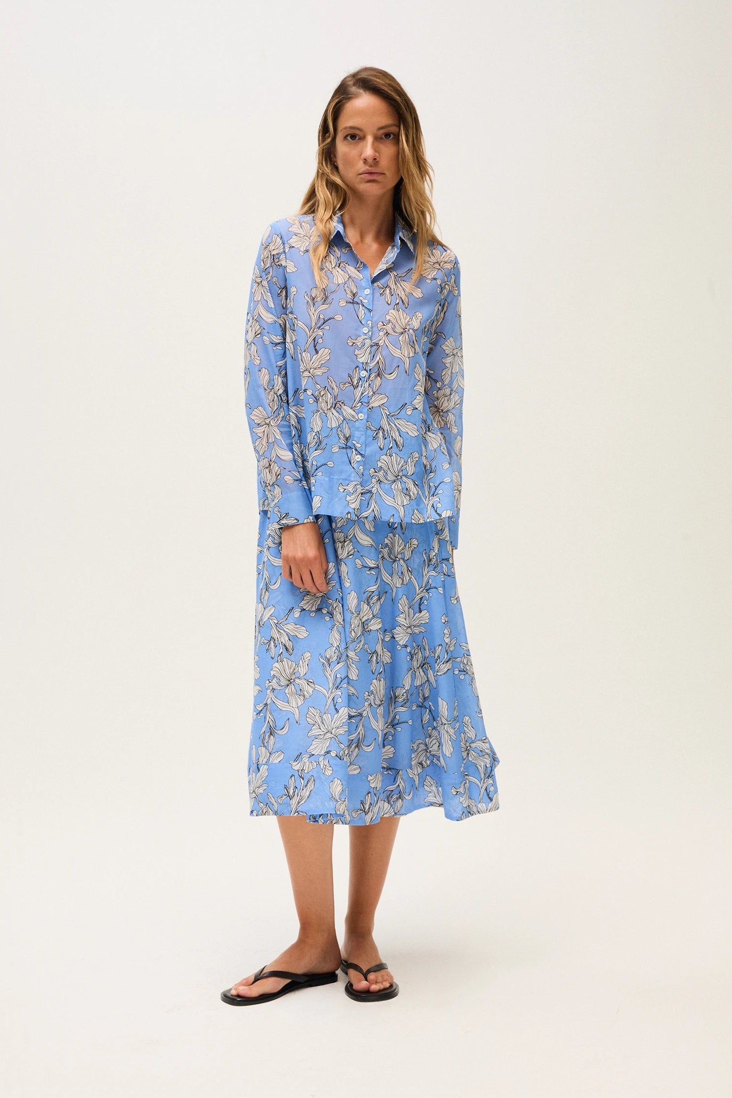 Woman wearing a blue blouse and skirt on a white background.