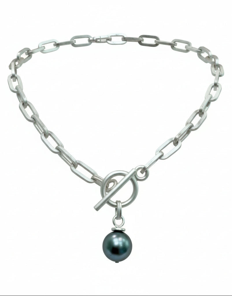Silver chain necklace with a dark blue/green pearl charm with a white background.