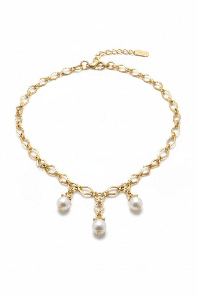 Gold chain necklace with pearl charms on a white background.