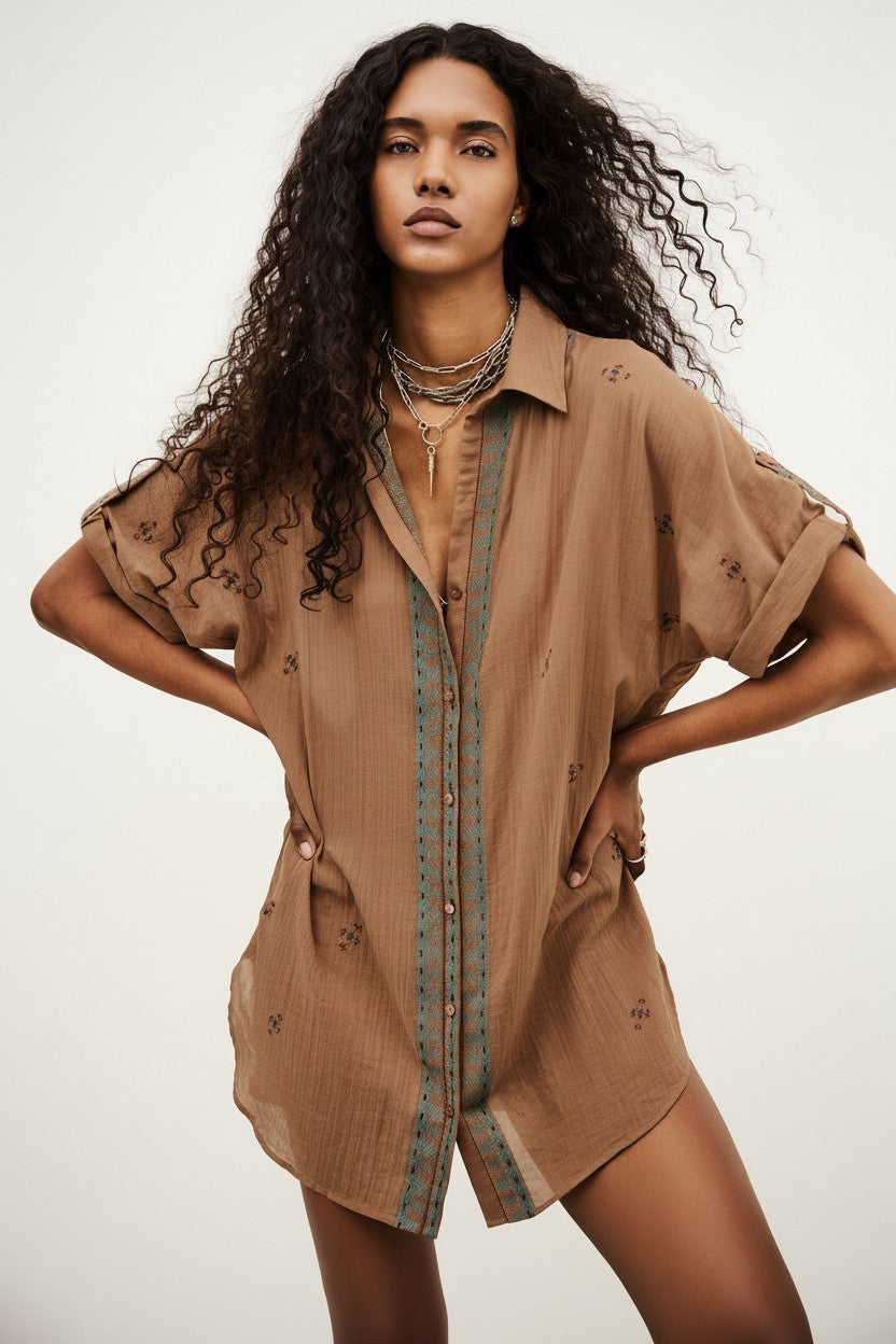 Woman wearing a brown outfit with a plain background.