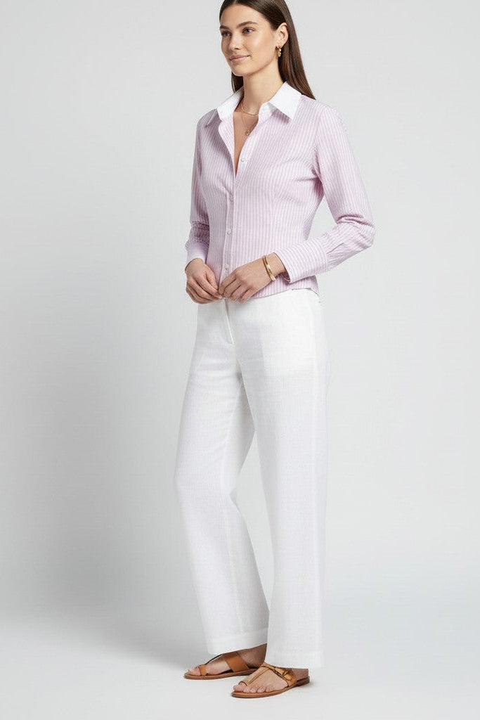 Woman wearing a pink striped shirt and white pants on a plain background.