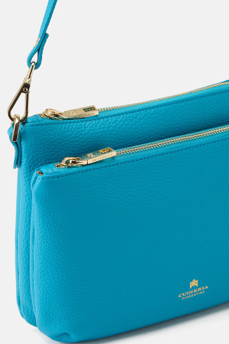 Blue handbag with gold zipper and visible brand logo on a white background.