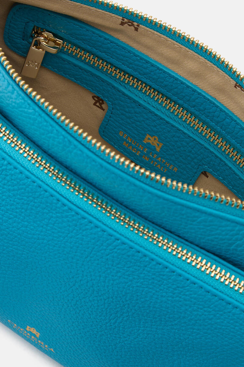 Close-up of a blue leather handbag with gold zipper and visible brand logo.