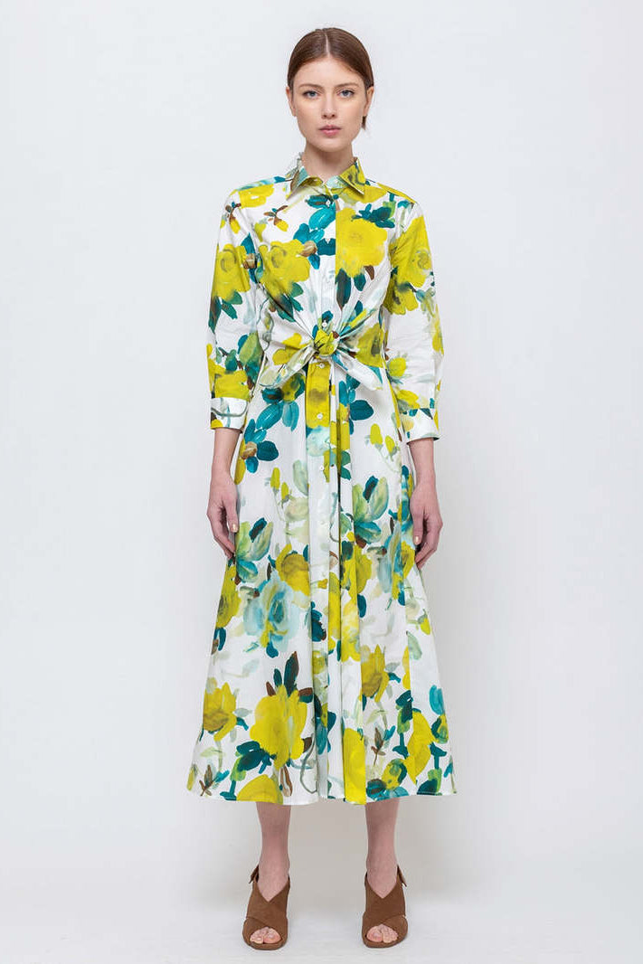 Woman wearing a floral dress with brown heels on a white background.